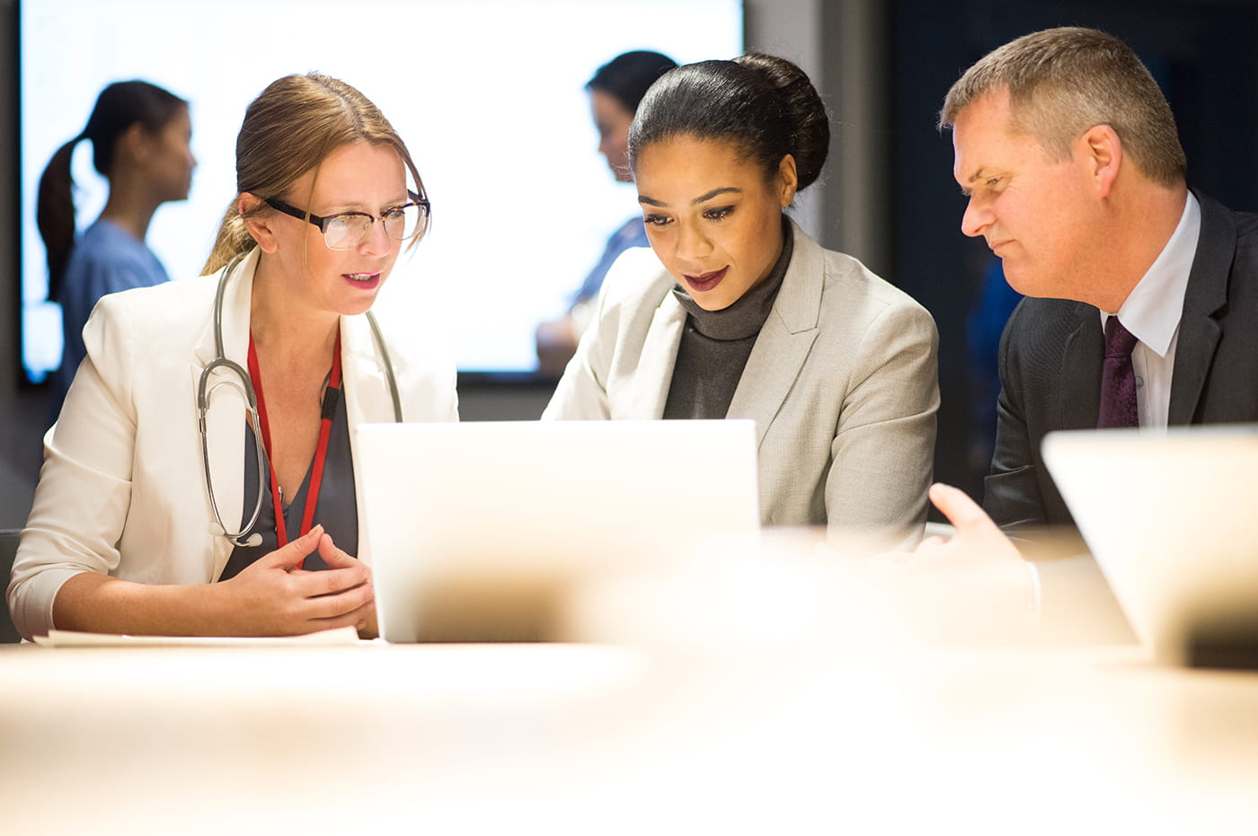 two female doctors and a male business man looking at a laptop