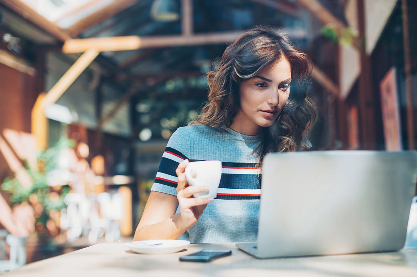 A woman working on a laptop with a cup of coffee.