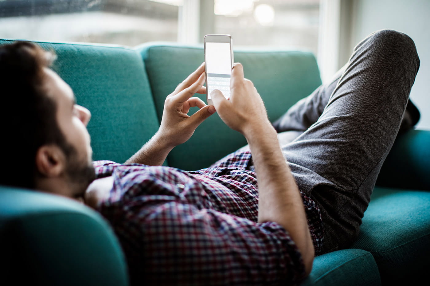 Man lying on a couch texting on his cellphone.