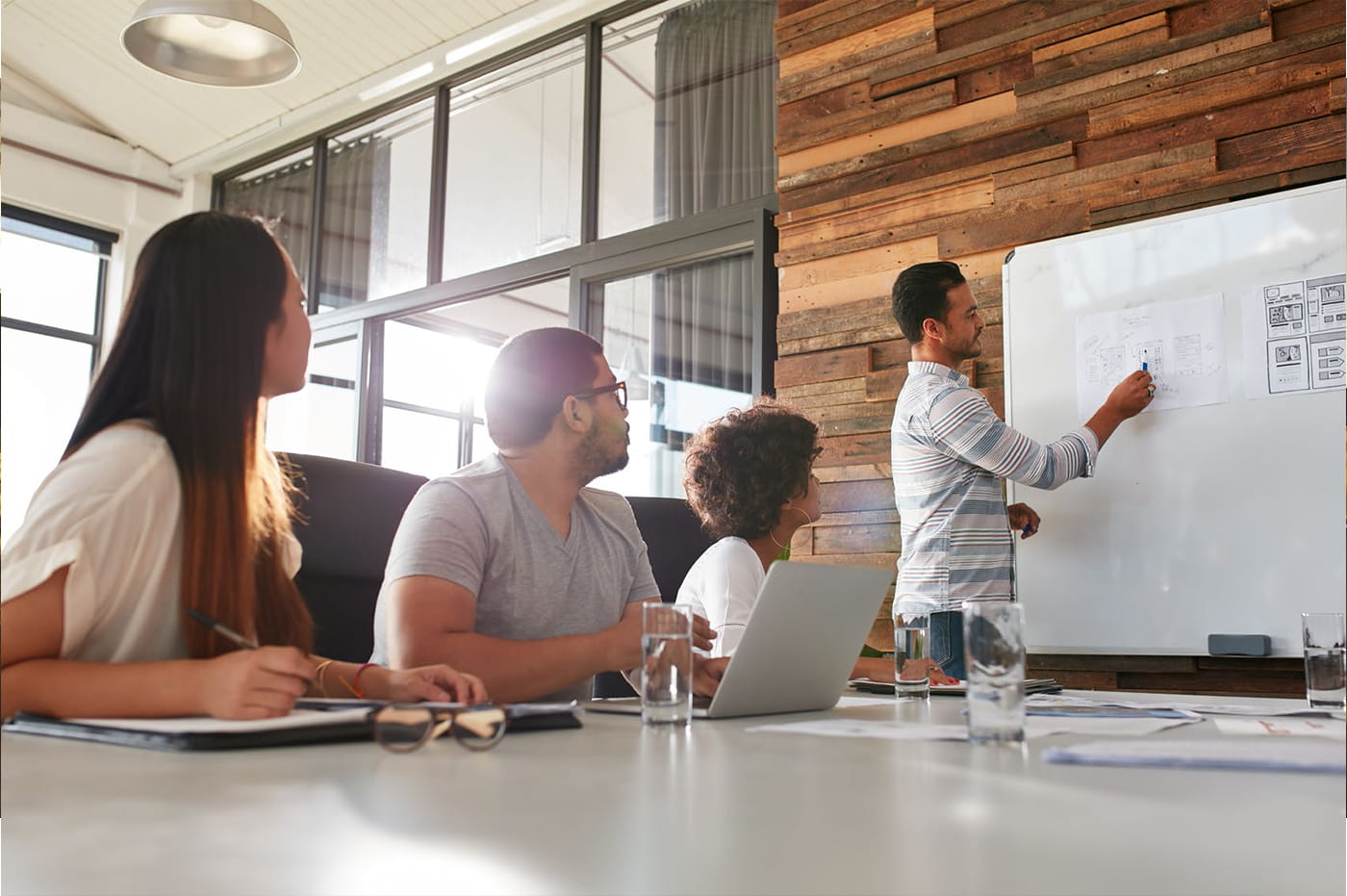 A team of coworkers strategizing on a white board.