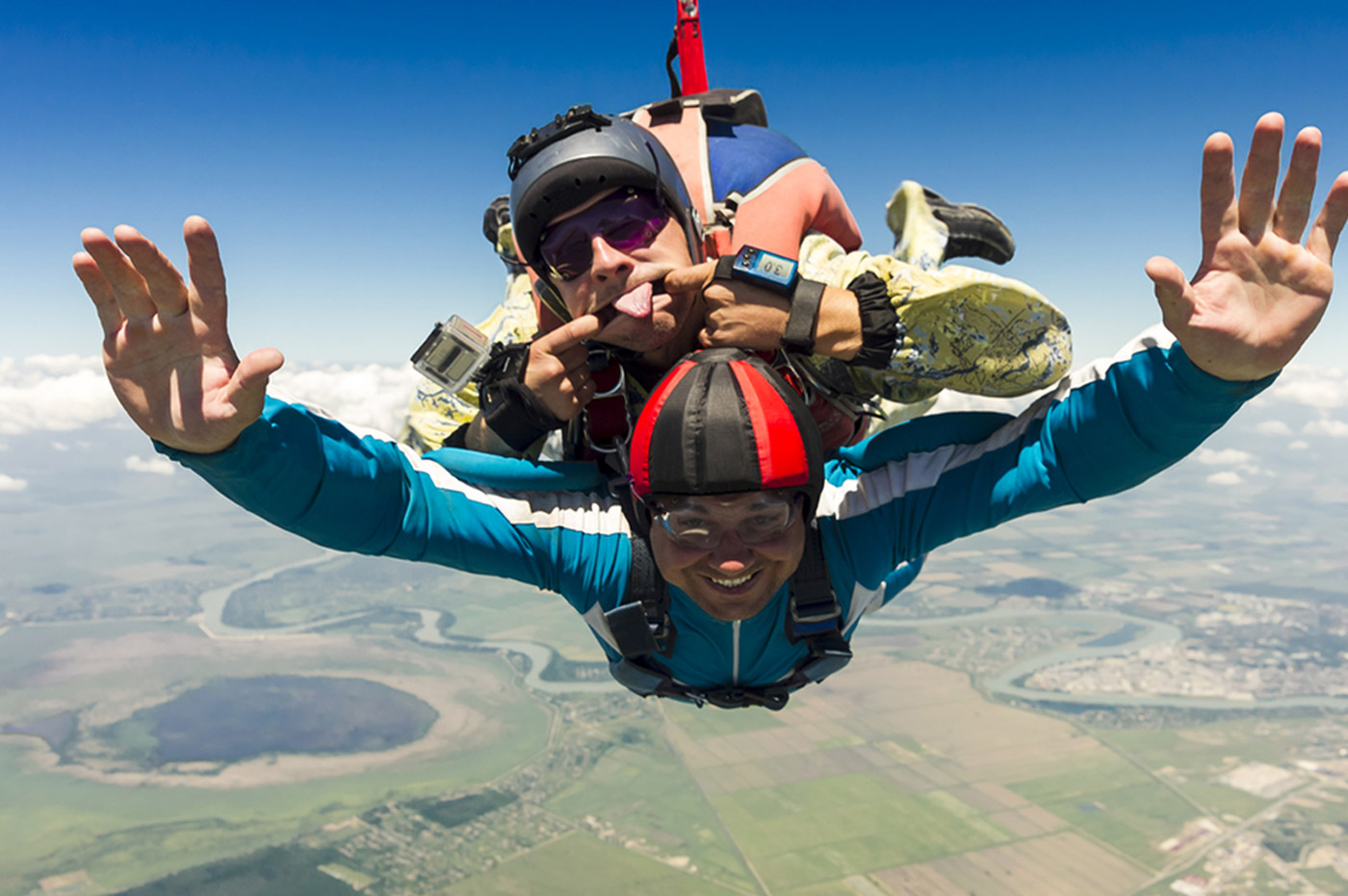 Two men skydiving, one man is making a funny face at the camera.