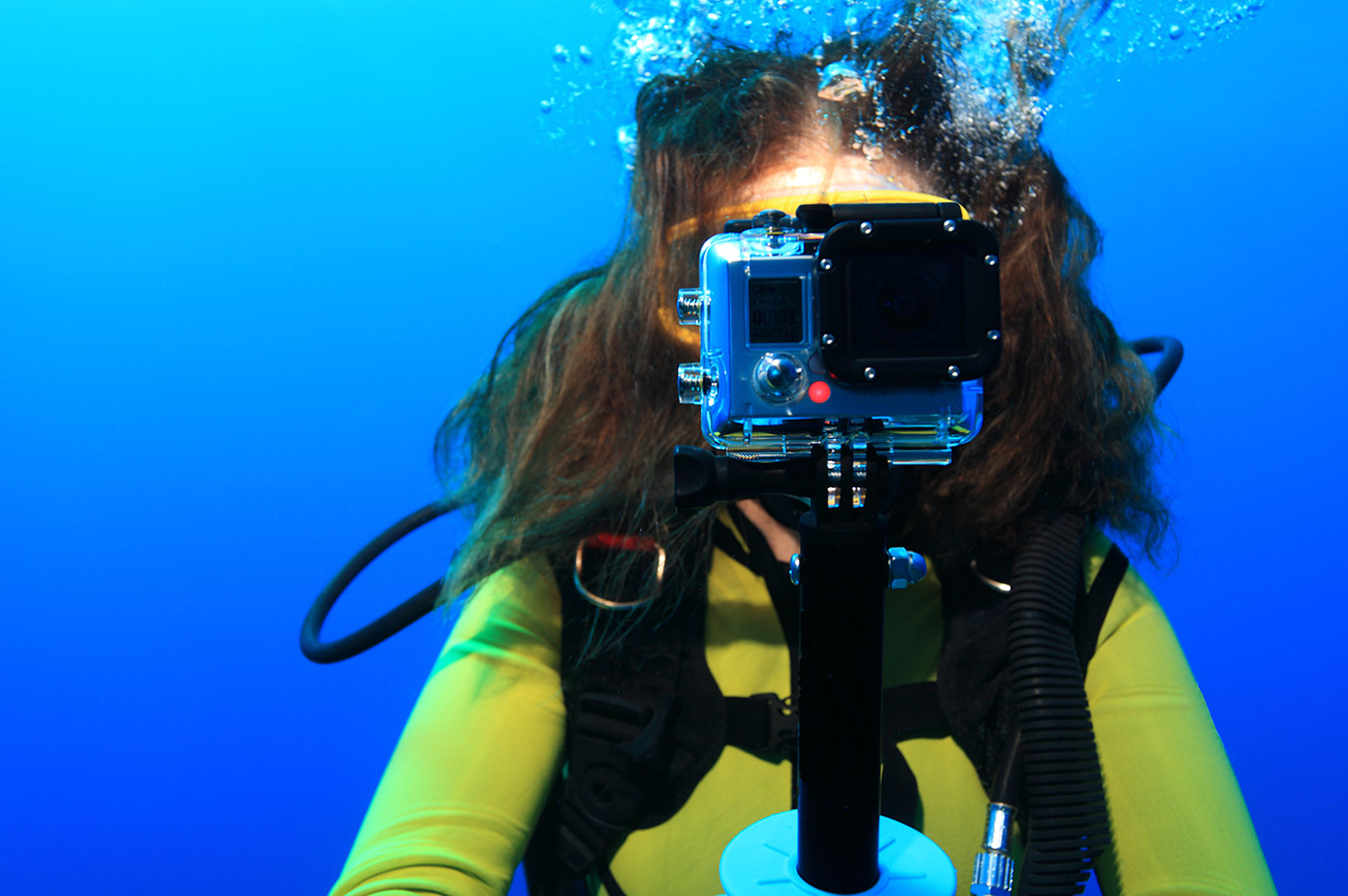 Woman snorkeling underwater with a GoPro camera.