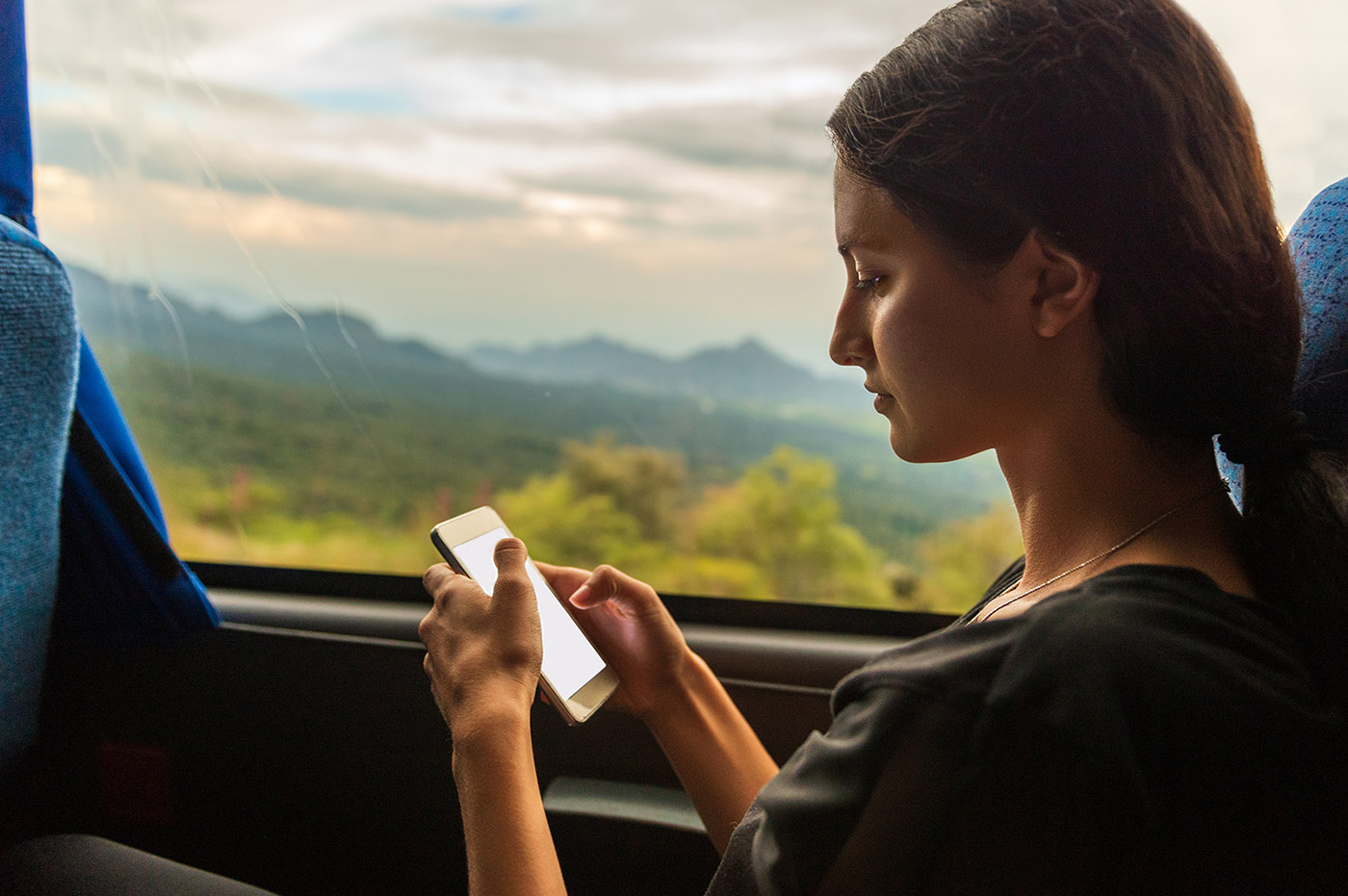 A young woman texting on her phone while traveling on a bus.