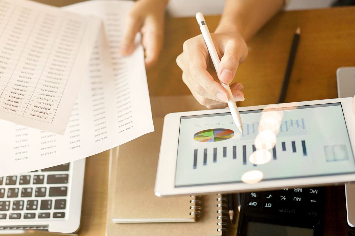 Data and charts on paper and and iPad screen.