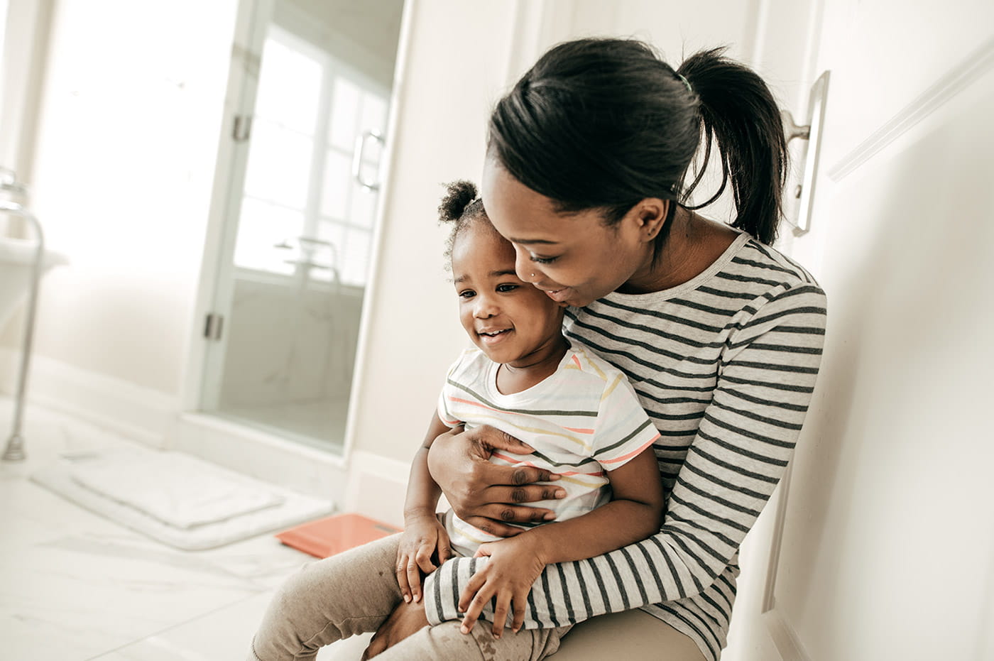 A young African-American mother holding her daughter on her lap.