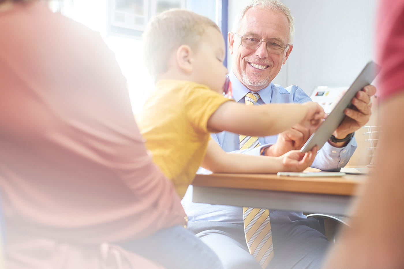 An older man and a little boy tapping on an iPad together.