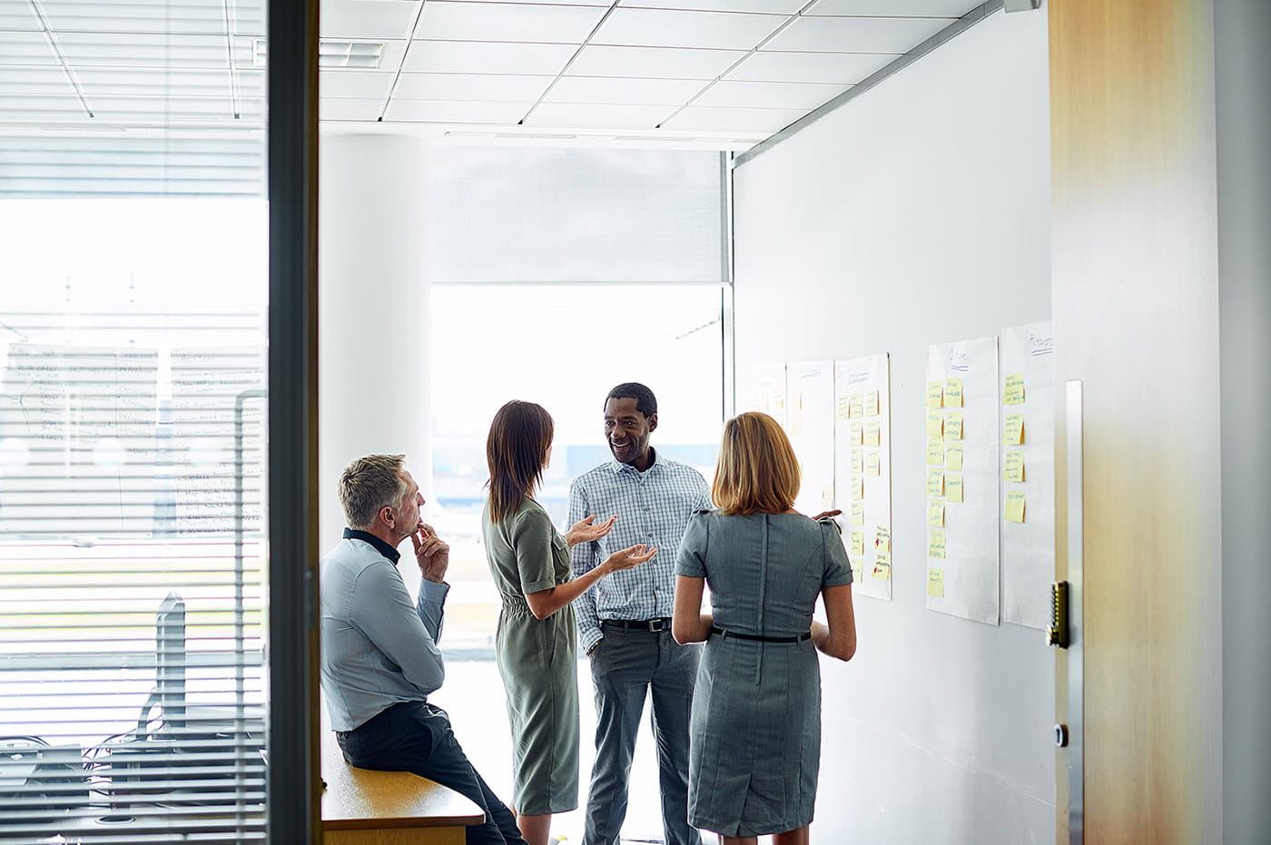 A group of professionals looking at a board full of sticky notes and discussing.