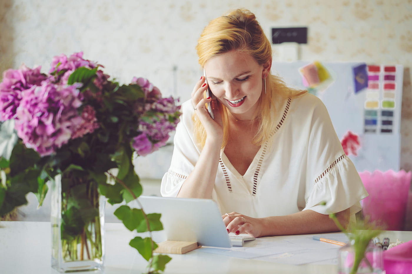 A woman working on an iPad and talking on her cellphone.