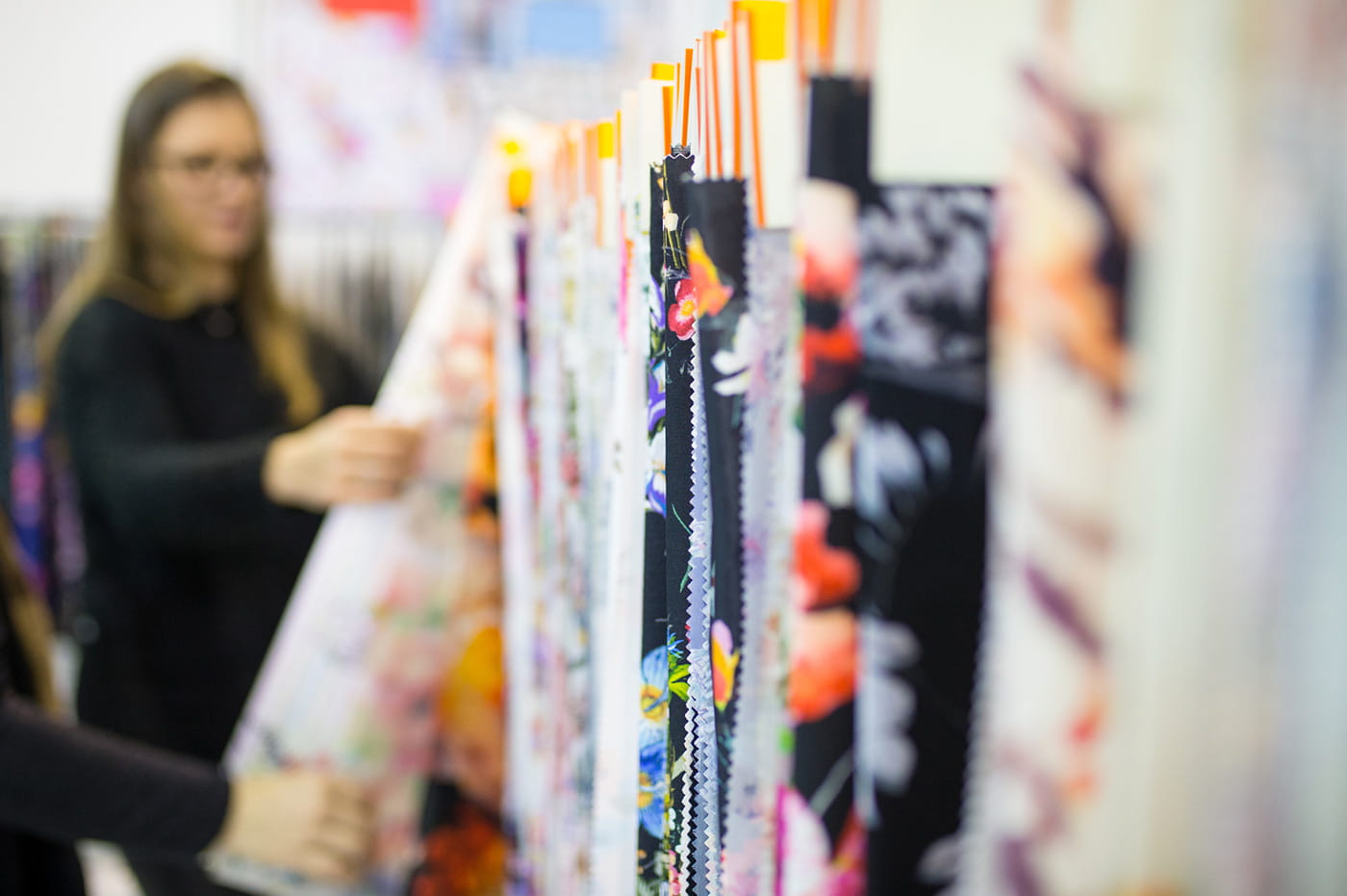 A woman browsing through different bolts of patterned fabrics.