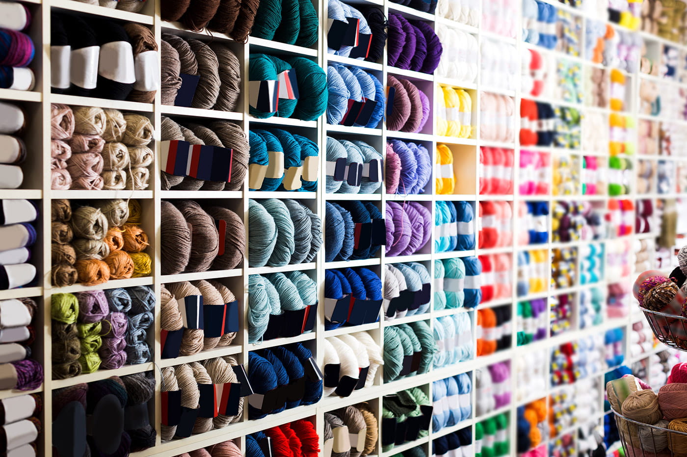 Large white shelves filled with different types and colors of yarn.