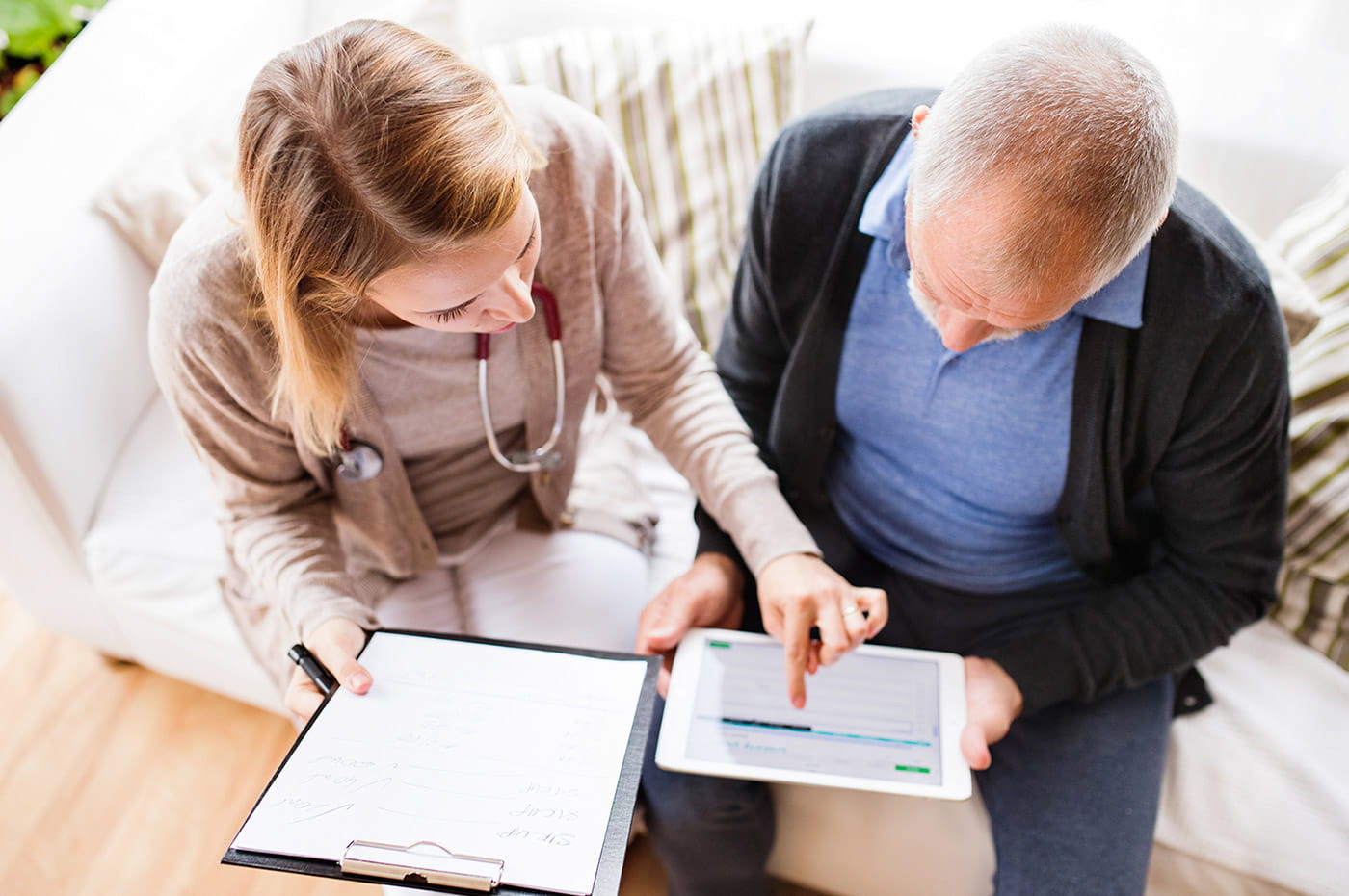 A healthcare worker and older patient looking at a chart on an iPad together.