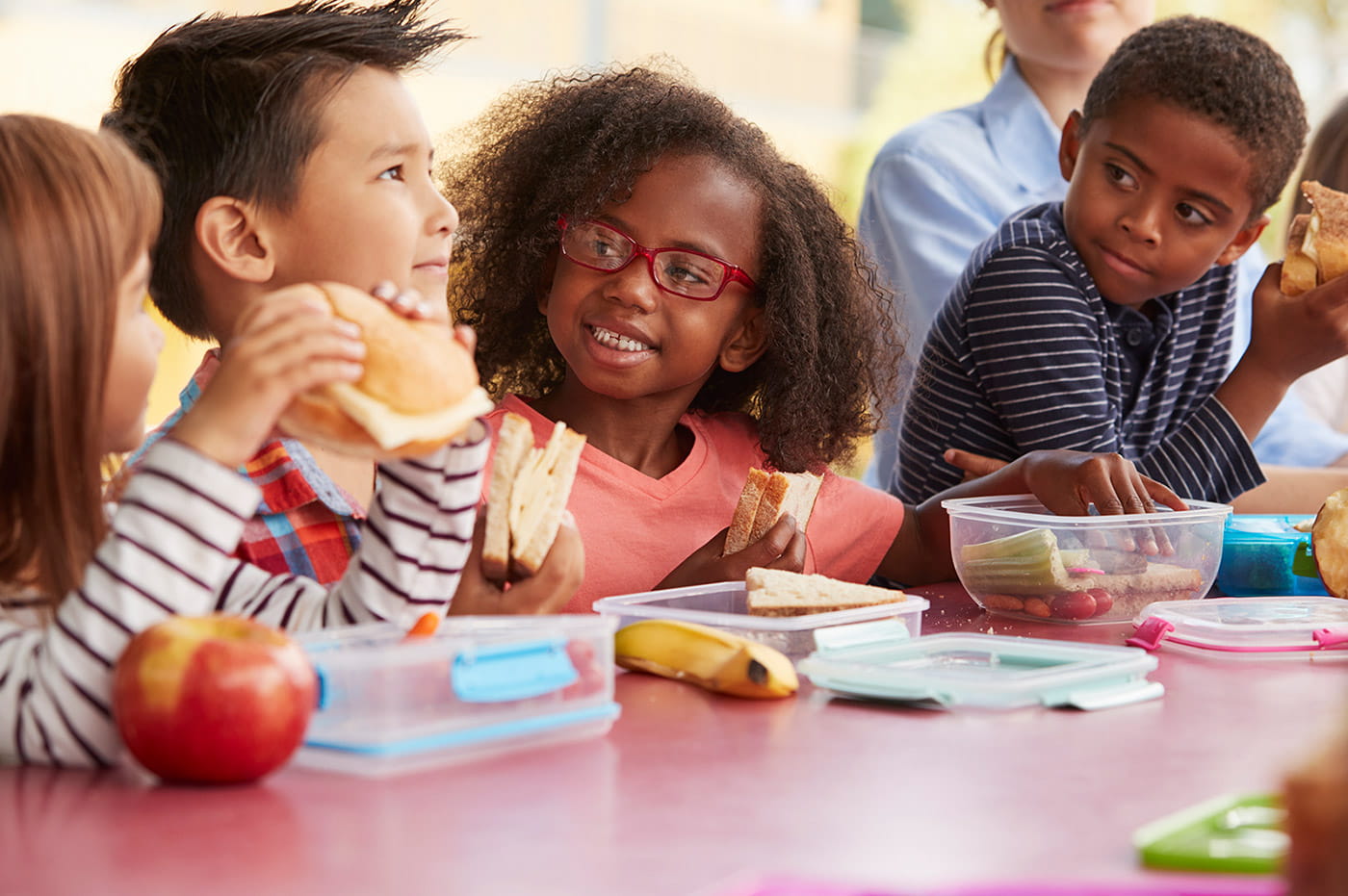 A group of children sitting together at school eating lunch.