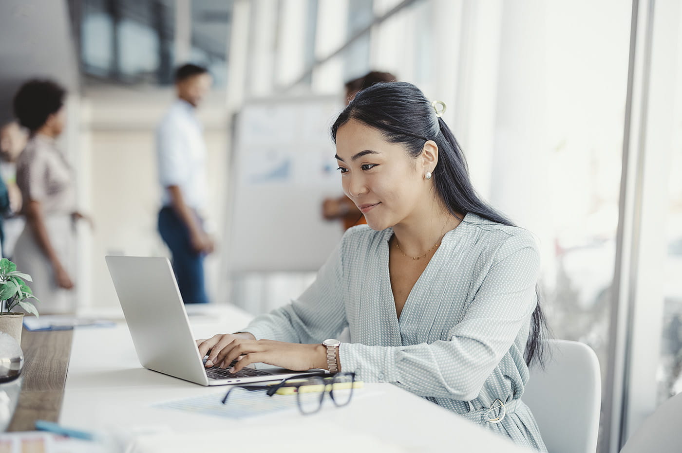 A woman working on her laptop in an office space.