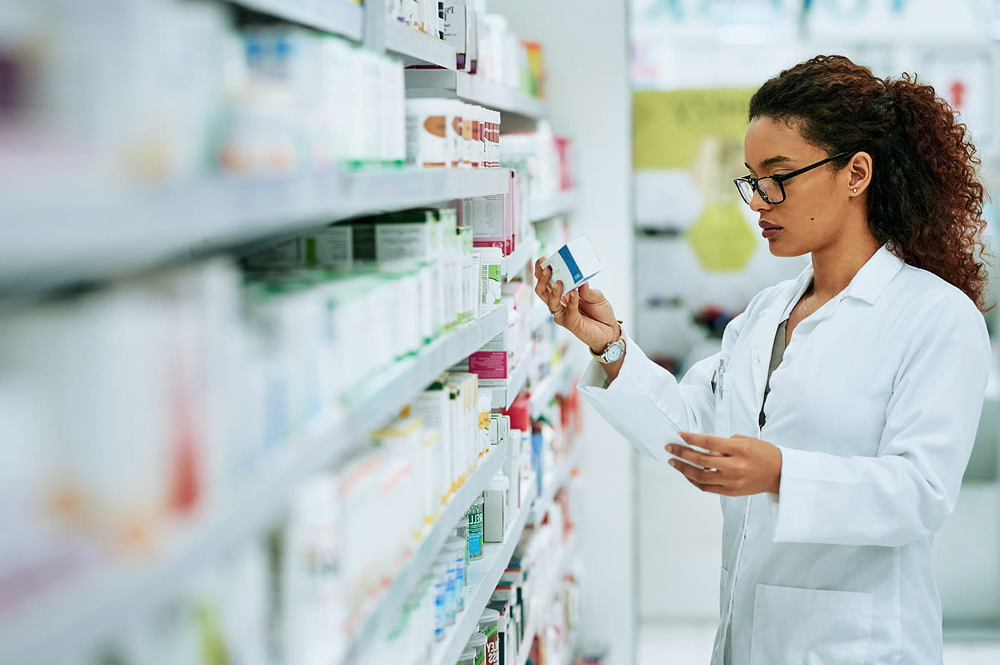 A healthcare worker looking at a box of medicine in a pharmacy.