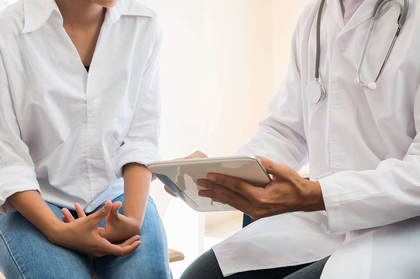 A doctor pointing to something on an iPad while talking to a patient.