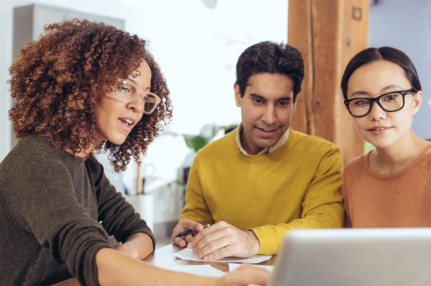 Two women and a man looking at a laptop and talking.