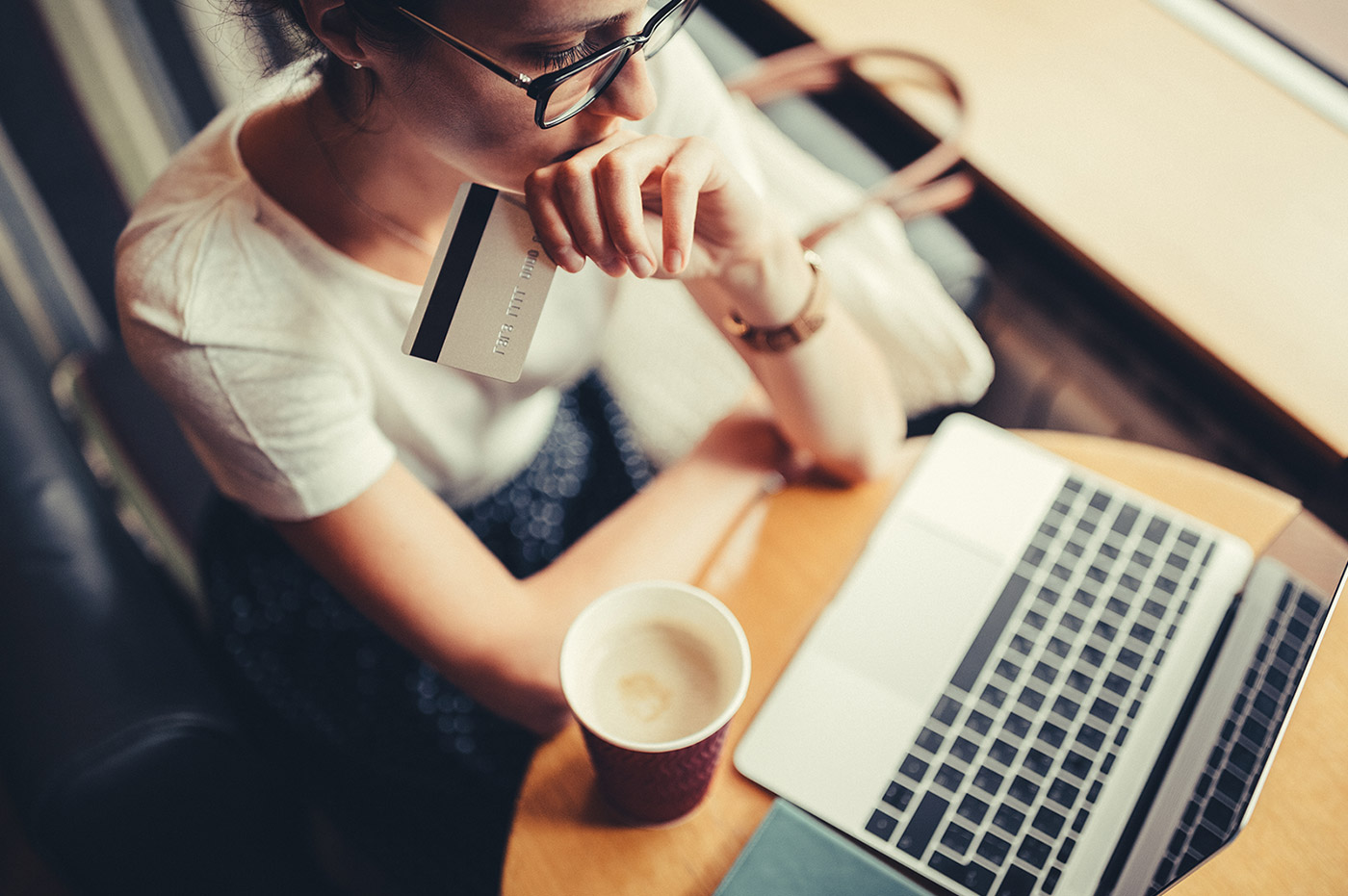 A woman looking at a laptop and holding her credit card.