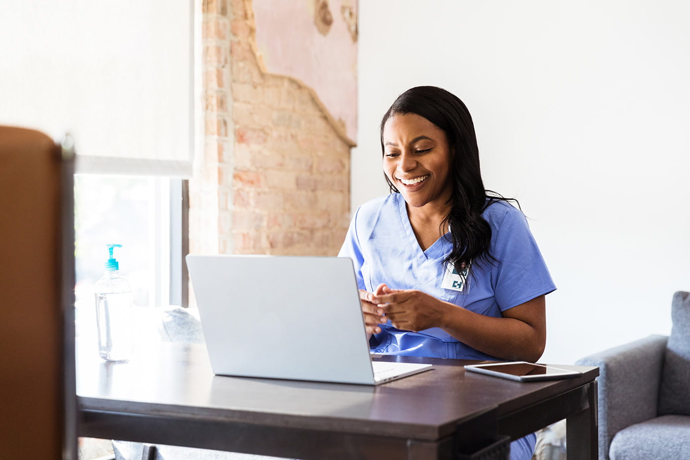 A female heathcare worker in scrubs on a video conference.