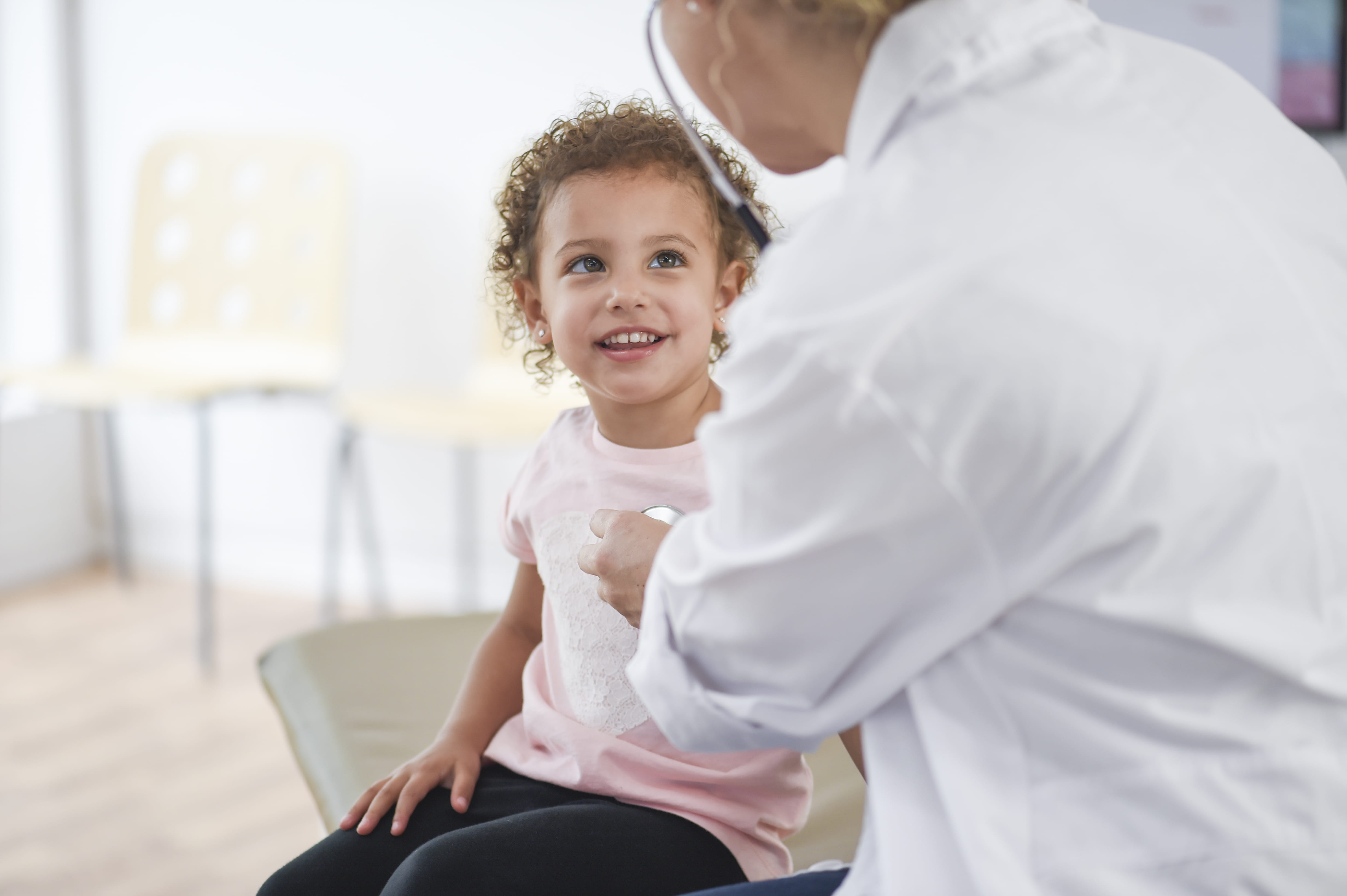 A doctor listening to a young girl's heartbeat with a stethoscope.