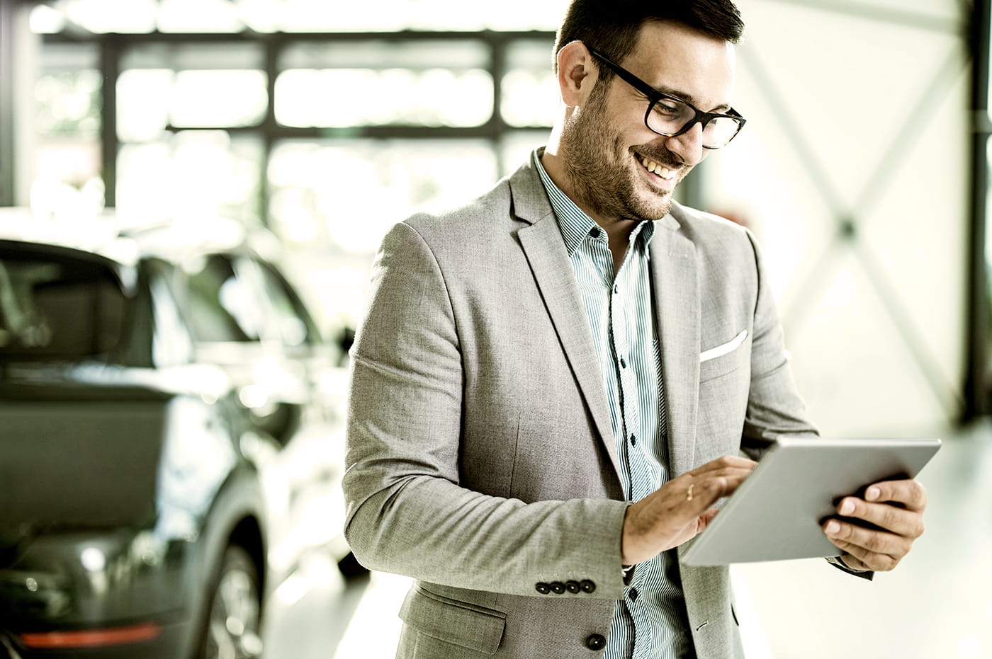 A man working on an iPad in a car showroom.