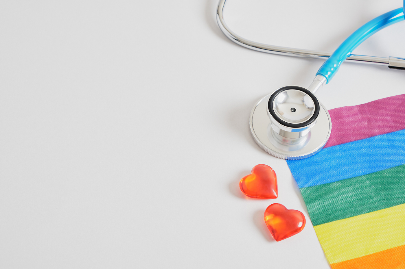 Pride Flag and tiny red hearts with a stethoscope.