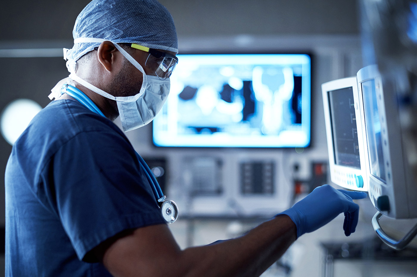 A healthcare working looking at monitors in an operating room.