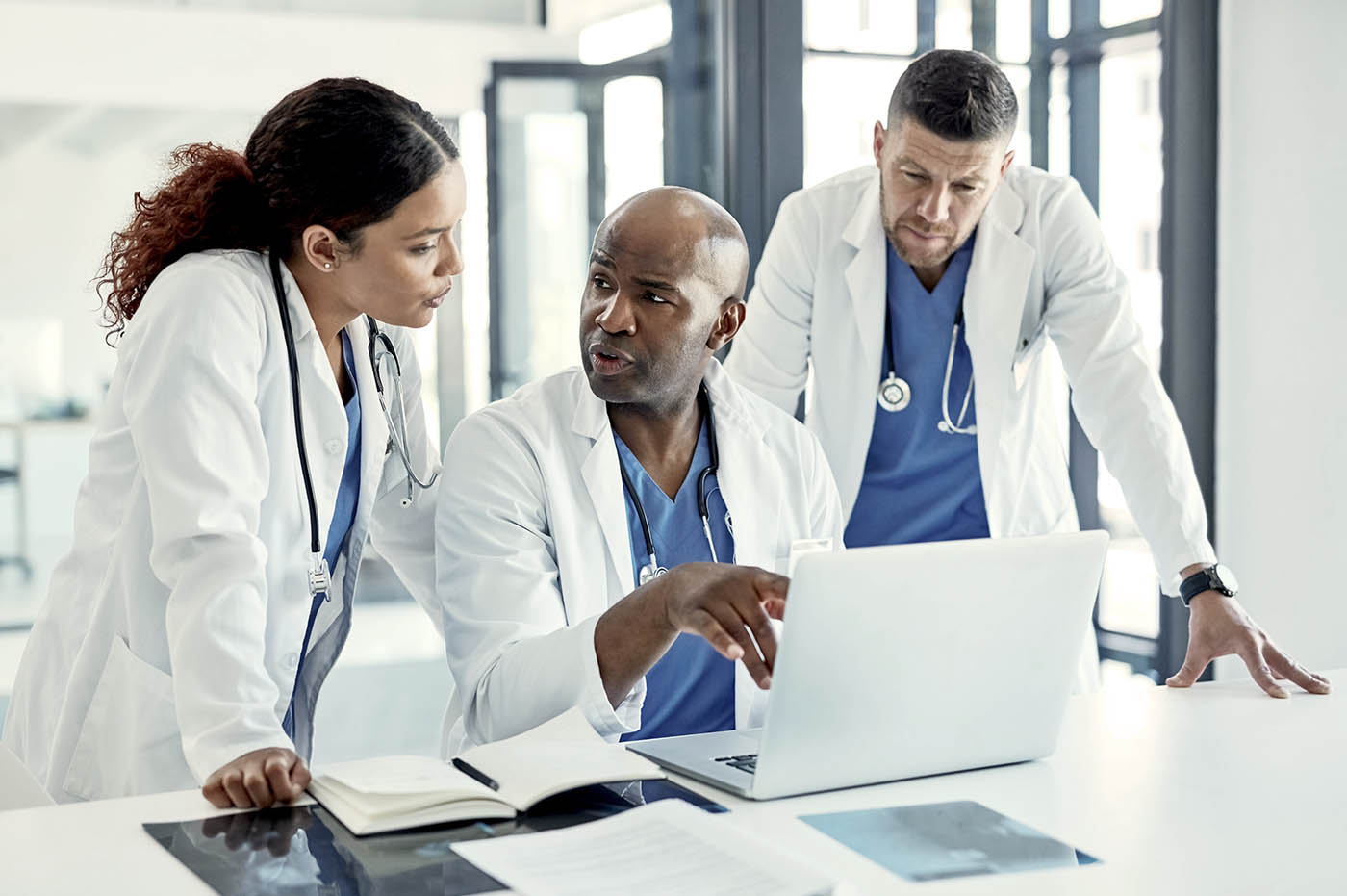 Three doctors looking at a laptop and discussing.