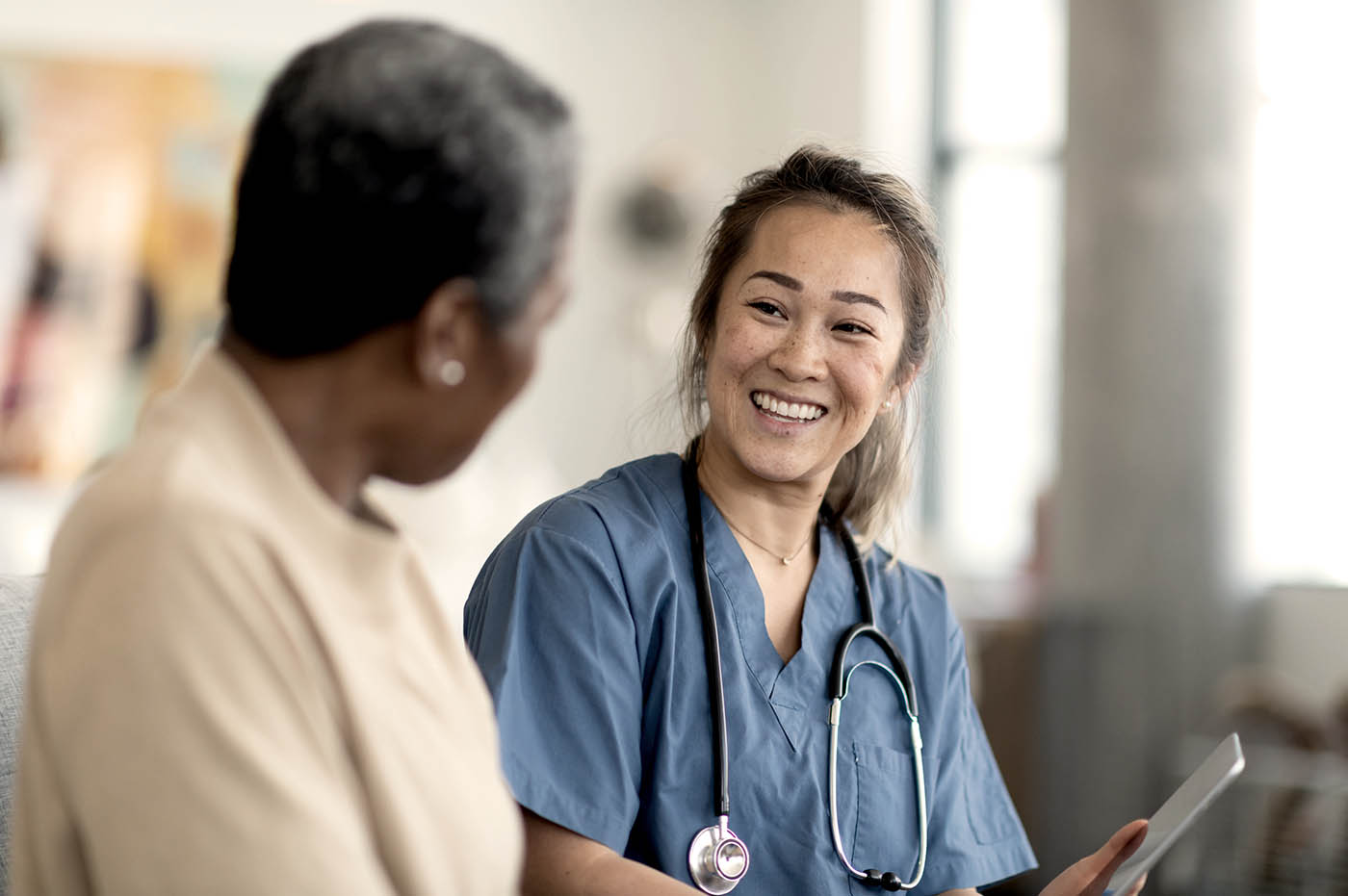 A female healthcare worker talking with a patient and smiling.