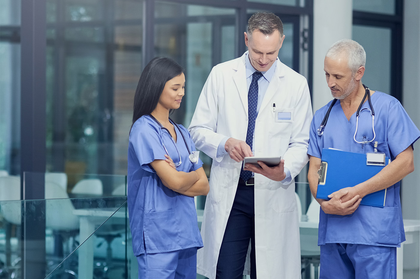 Three healthcare workers looking at something on a tablet and discussing it.