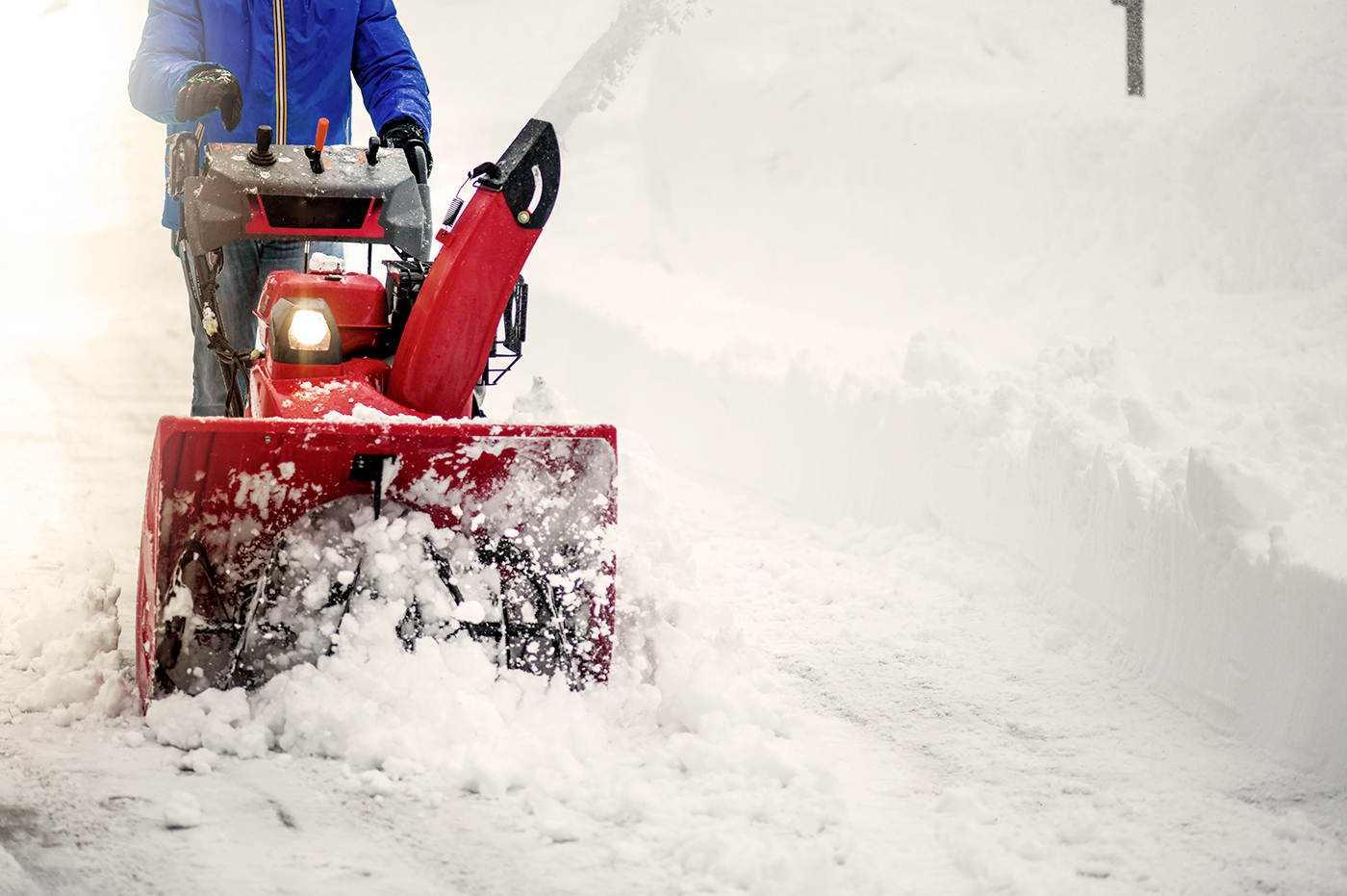 A person using a snow thrower to clear snow.