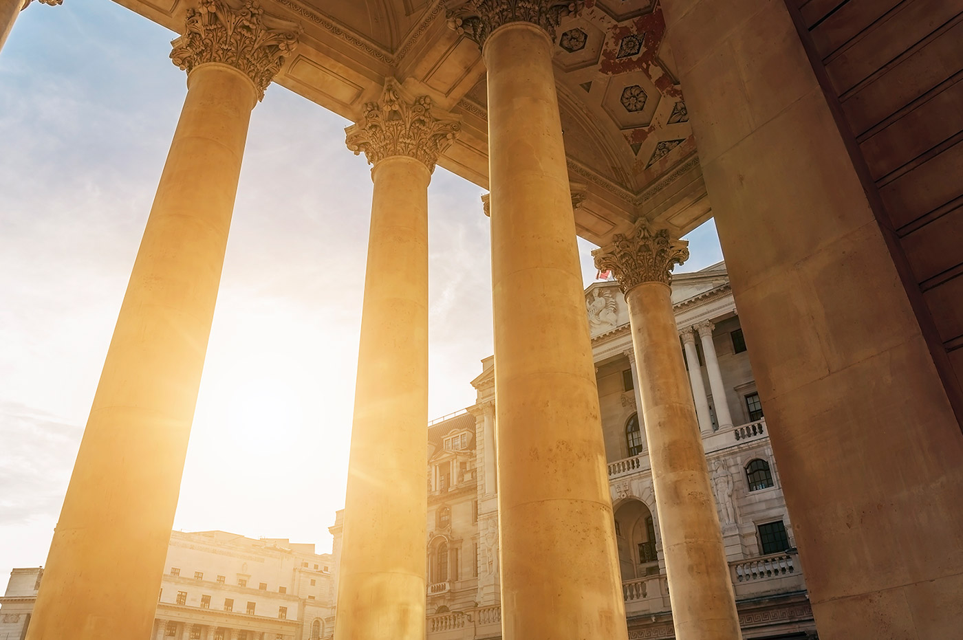 A row of Corinthian columns attatched to a large building in the sunset.