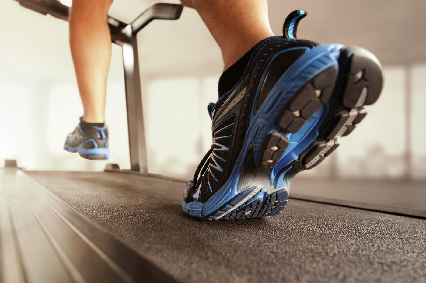 Tennis shoes of someone running on a treadmill.