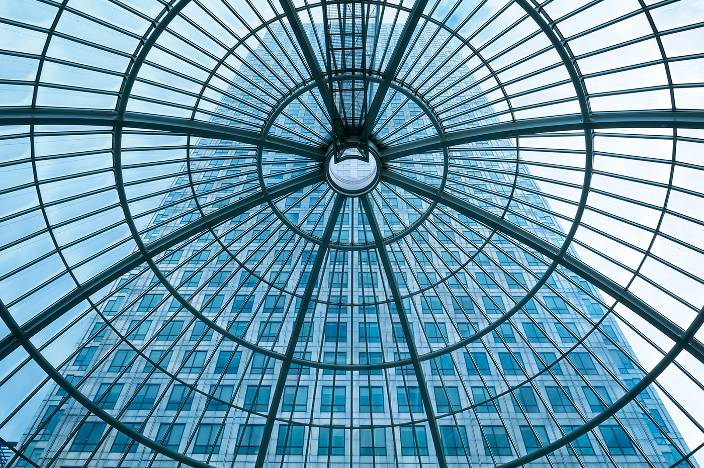 A high-rise building through the view of a glass and steel domed window.