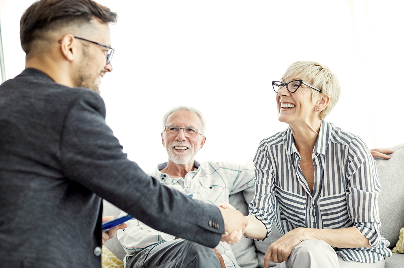 Business man talking and shaking hands with an older couple.