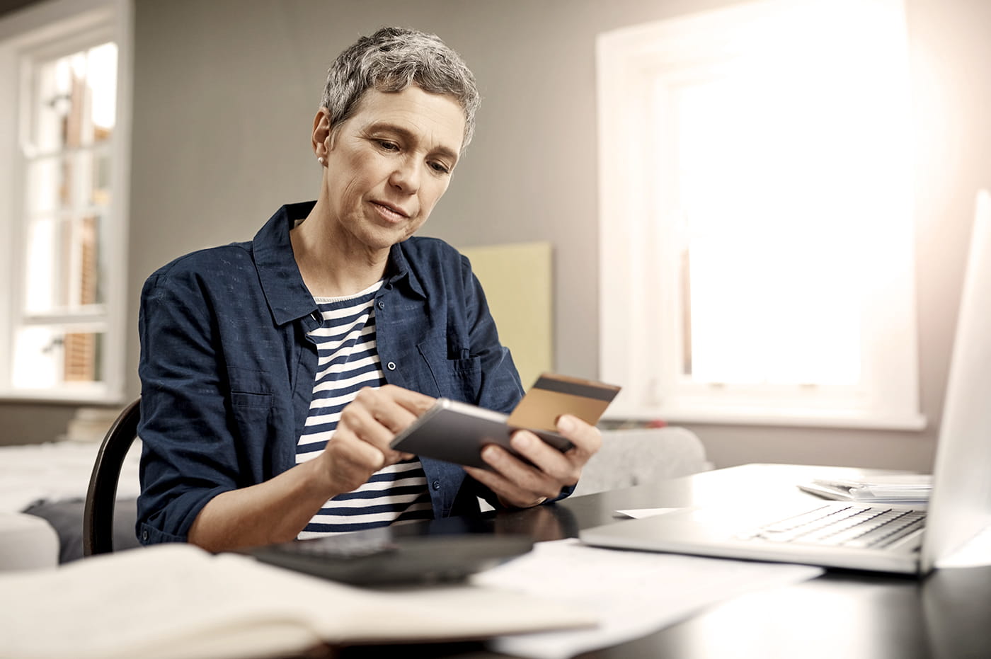 Woman doing online shopping on cellphone and using her credit card.