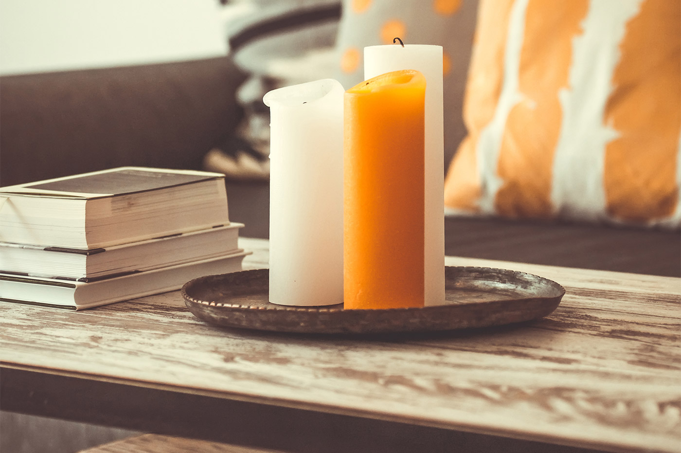 A coffee table with some books and 3 large candles.