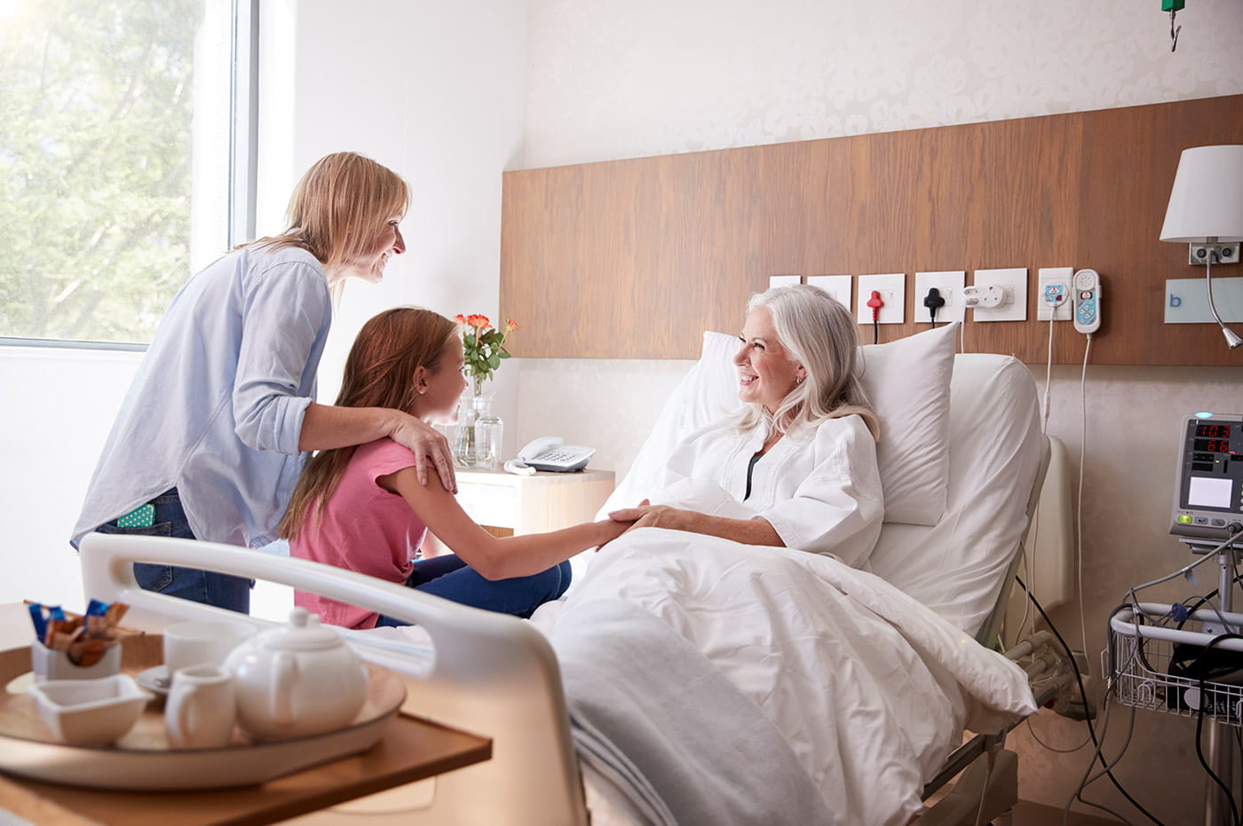 A mother and daughter visiting their grandmother in the hospital.