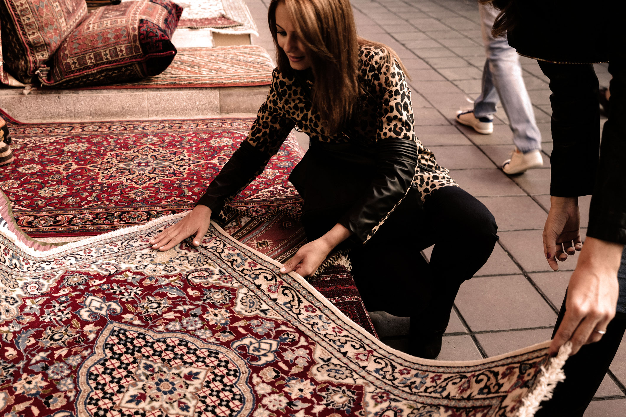 A woman looking at several oriental rugs.