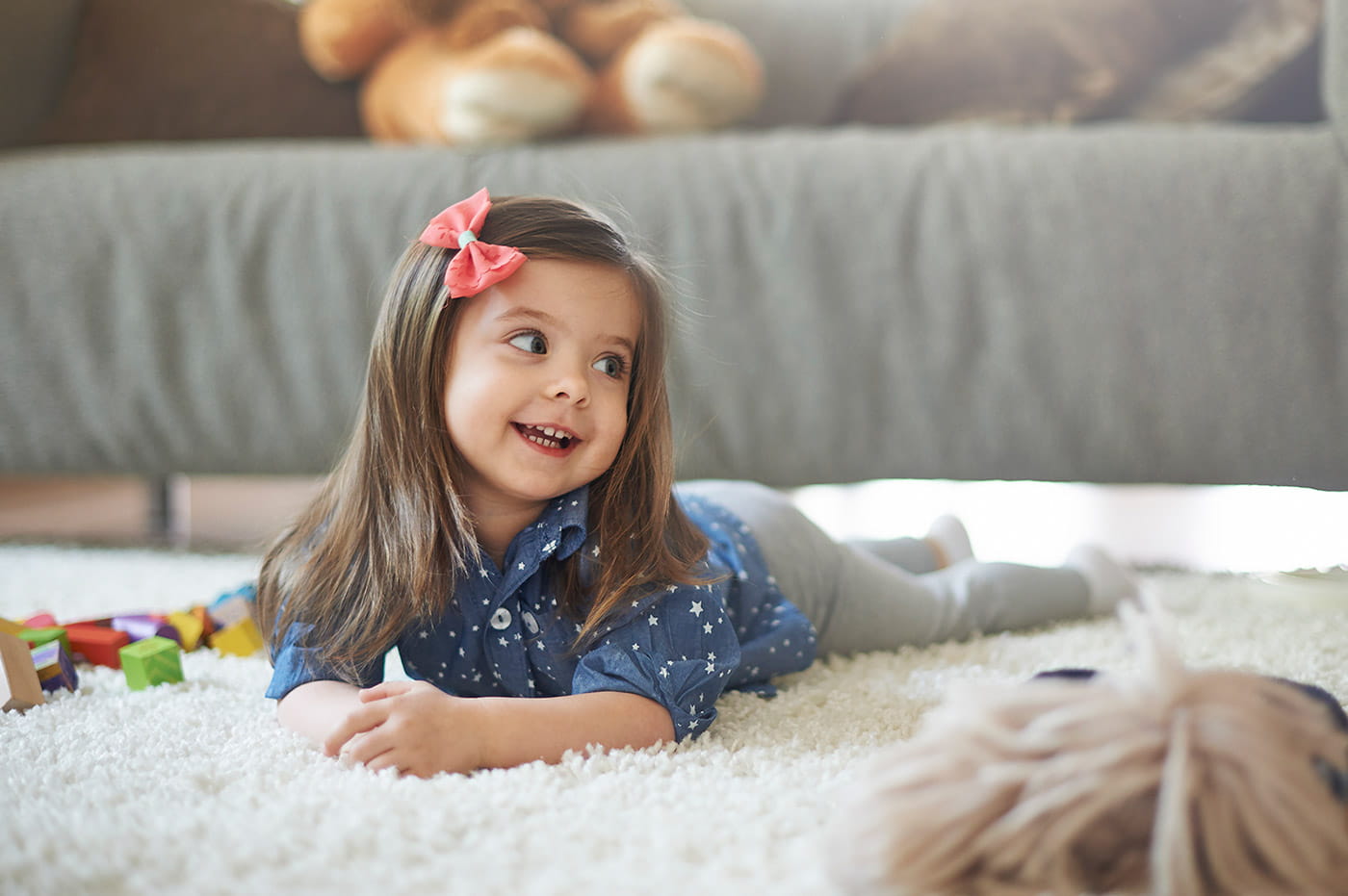 A young girl playing on a living room rug.