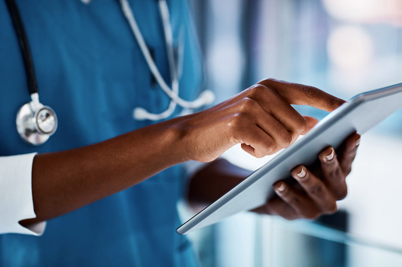 A healthcare worker's hands working on a tablet.