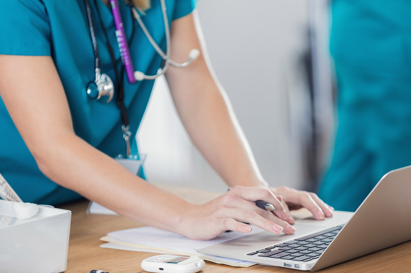 A female healthcare worker working on a laptop.