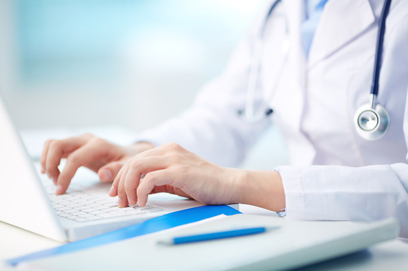 A doctor typing on a laptop.