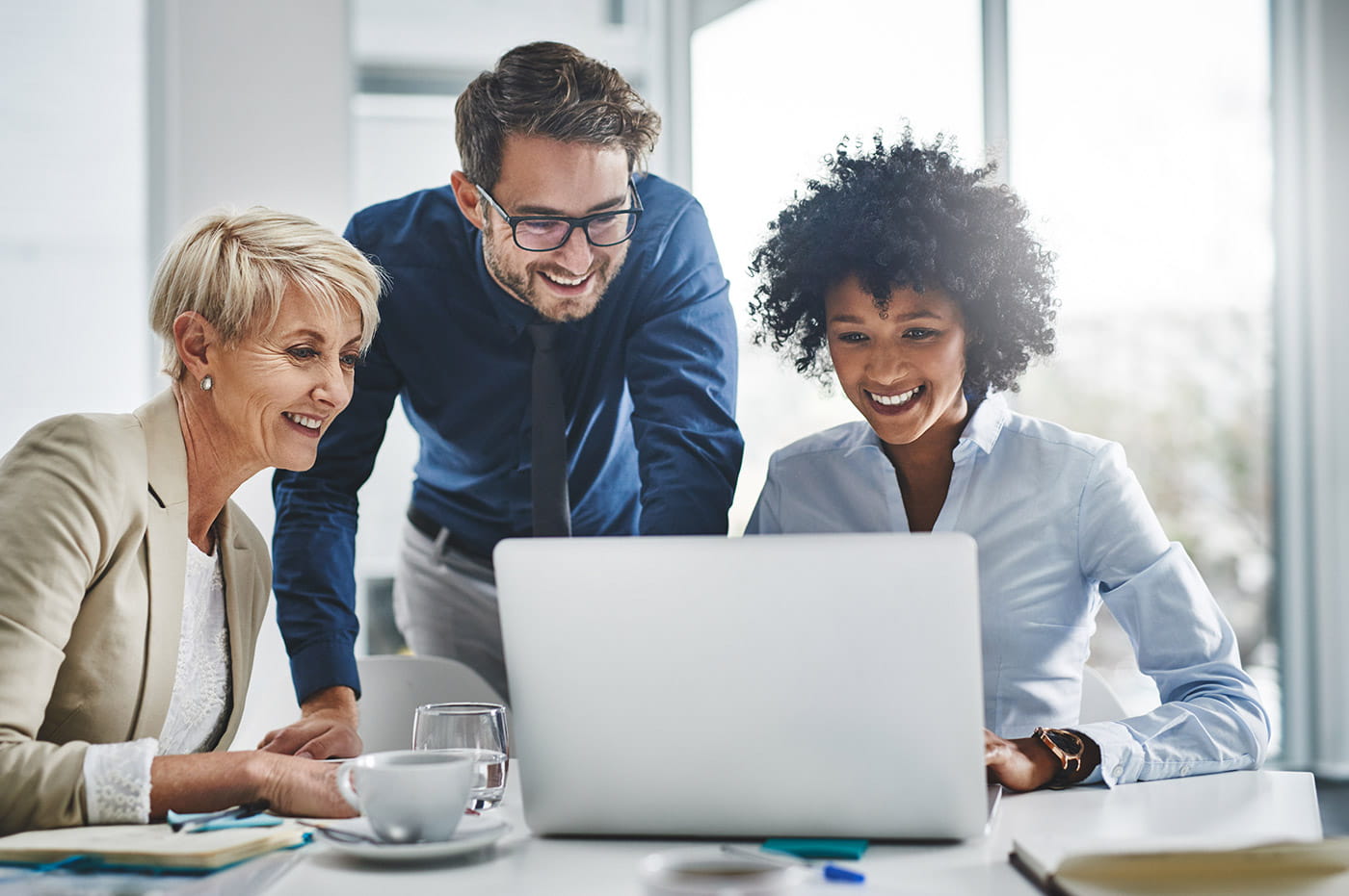 Three professionals working together on a laptop computer.