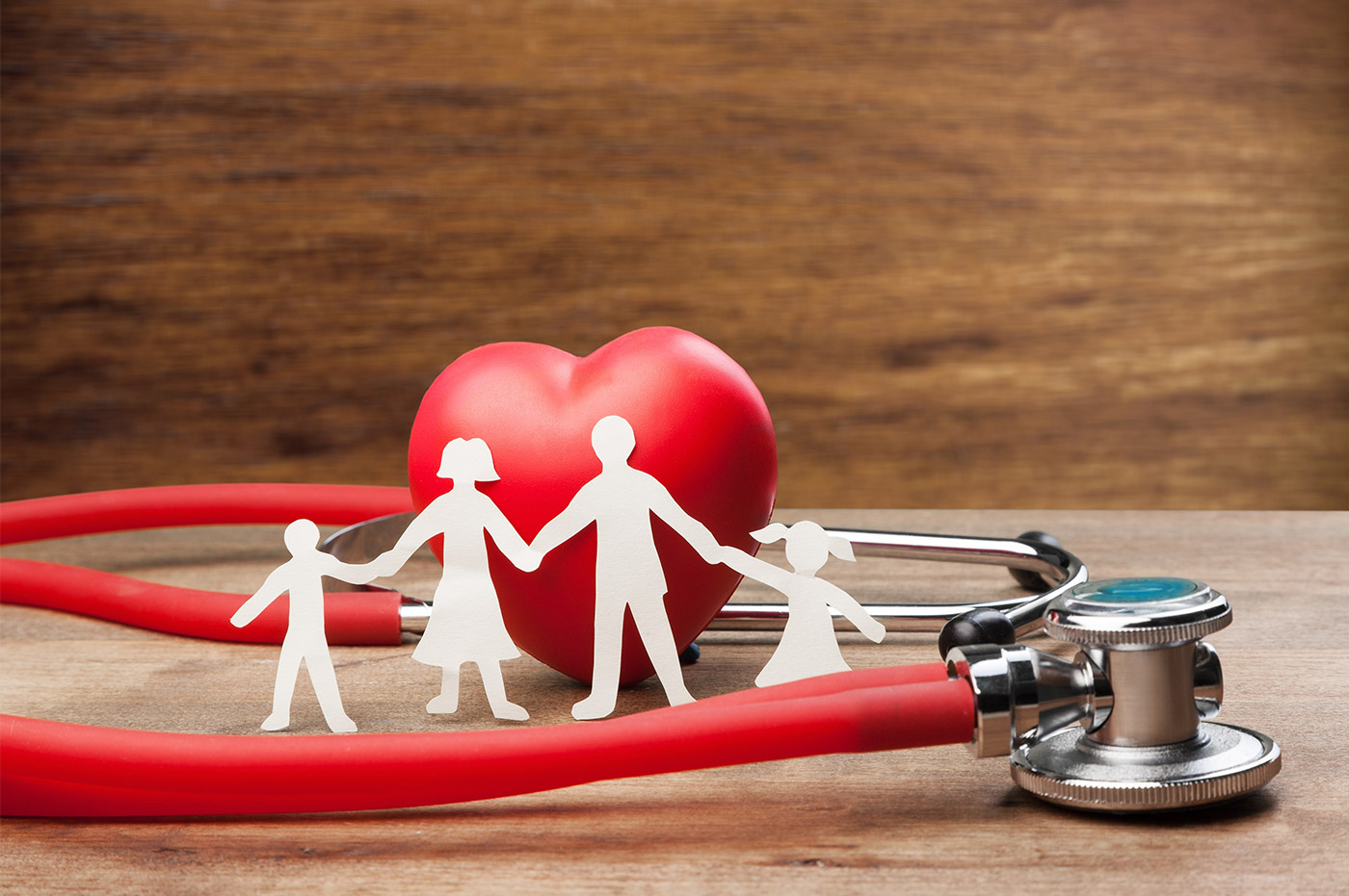 A papercutout of a family in front of a heart and stethoscope.