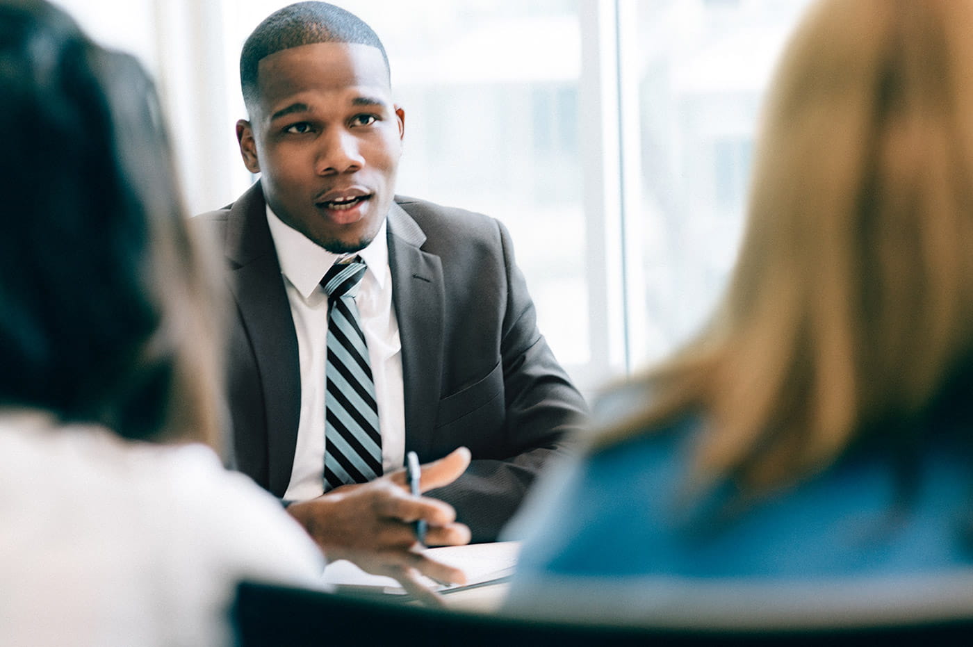 A business man talking to two women.