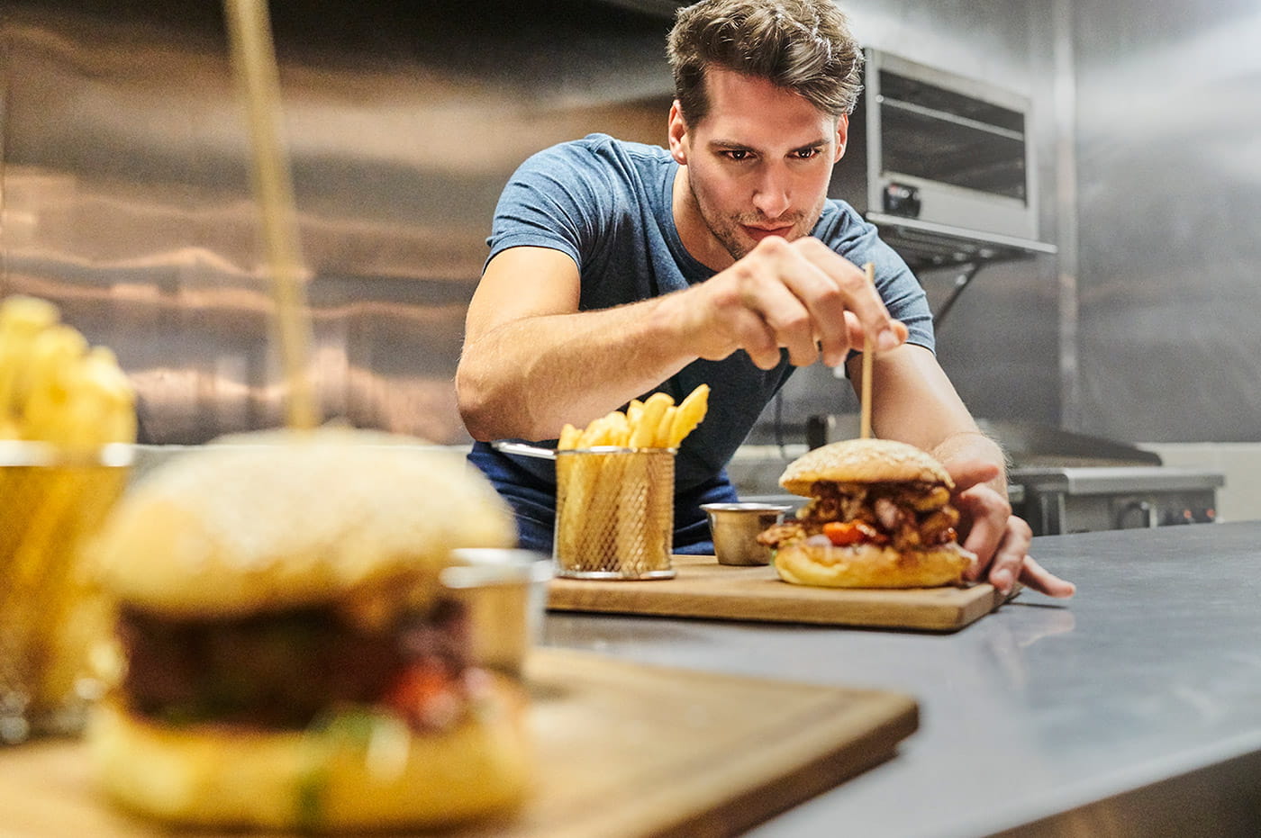 A man preparing hamburgers and french fries.