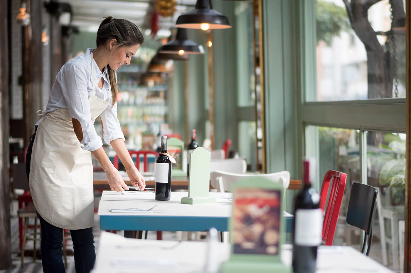 A waitress setting up tables at a restaurant.