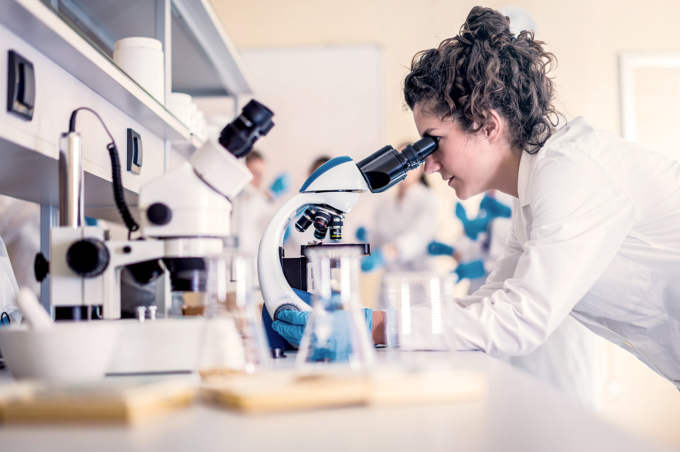 A female researcher looking at something with a microscope in a lab.