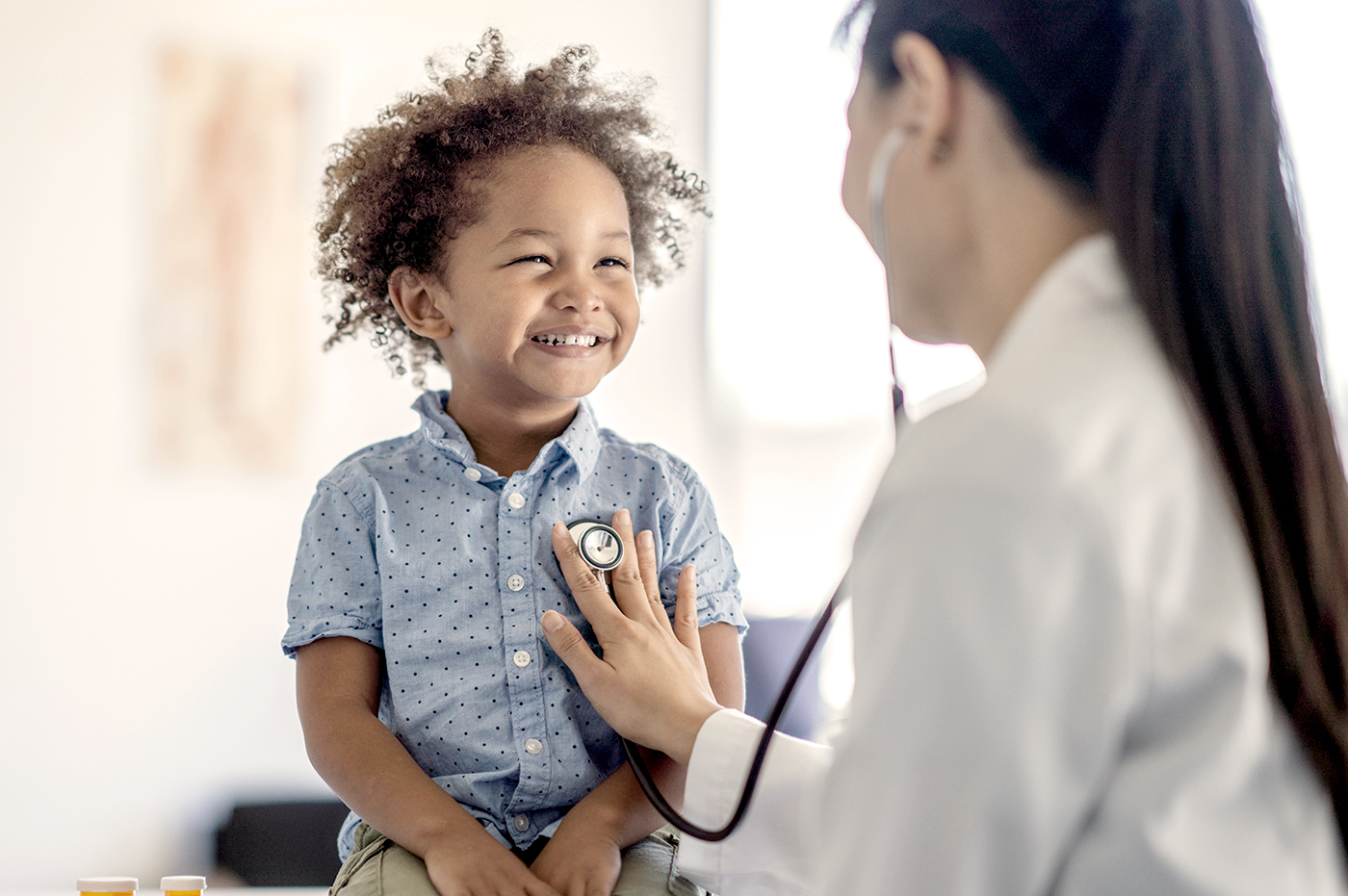 A doctor listening to a little boy's heartbeat using a stethoscope.