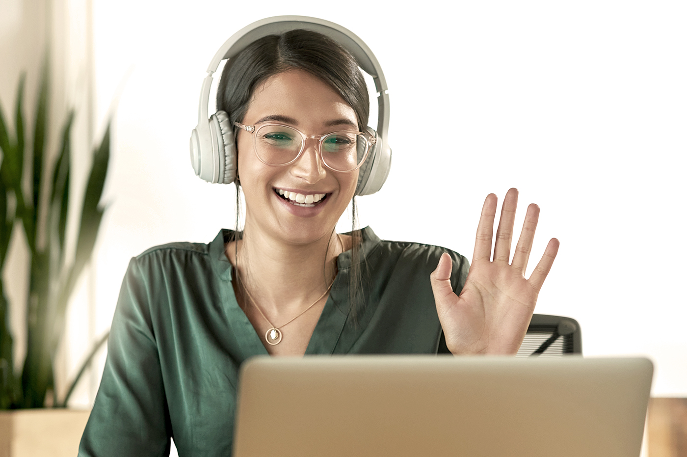 A woman greeting coworkers in an online video conference.